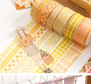 Detail van gele geblokte washi tape rollen met een decoratieve cartoon sticker