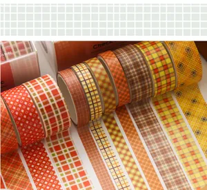 Close-up van geruite washi tape rollen met diverse patronen in warme oranje en geeltinten