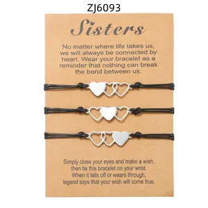 Close-up of three black braided heart bracelets on a decorative kraft 'Sisters' gift card.