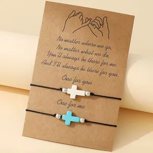 Close-up of handmade friendship bracelets with cross charms on a sentimental kraft card.