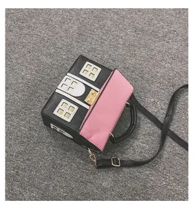 Macro view of a creative house-shaped crossbody bag with pink quilted flap and black base.