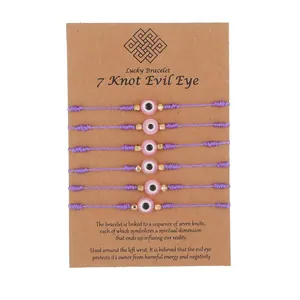 Handmade purple wax rope 7-knot evil eye bracelets set on brown cardboard display