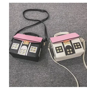 Detailed view of creative house-shaped crossbody bags in black and white with pink roofs