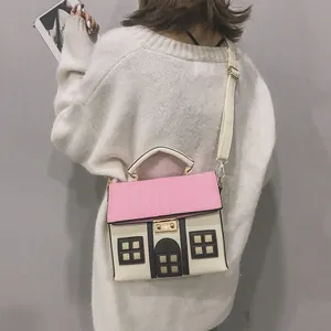 Detail shot of a model wearing a creative house-shaped crossbody bag with pink roof