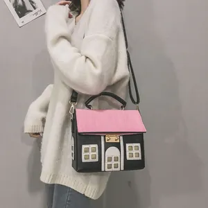 Close-up of a creative house-shaped crossbody bag worn by a model in a white sweater