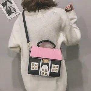 Close-up detail of a creative pink and black house-shaped crossbody bag worn by a model.