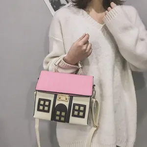 Creative cottage house shaped crossbody bag in pink and cream held by a model