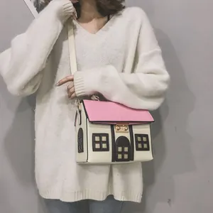 Close-up detail of a model carrying a creative cartoon house-shaped pink crossbody bag.