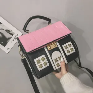 Detailed view of a creative pink and black house-shaped handbag with unique roof stitching.