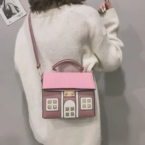 Detailed view of a creative pink house-shaped crossbody bag carried by a model