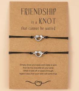 Detail view of two knot friendship bracelets on a brown wish card with black cords.
