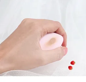 Close-up detail of a soft pink teardrop makeup sponge being held to show its texture