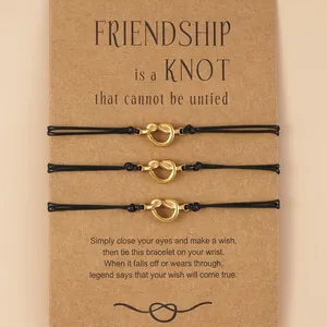 Set of 3 gold knot friendship bracelets with black wax cord on kraft paper card