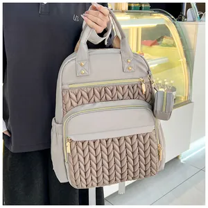 Nahaufnahme des grauen gesteppten Wickelrucksacks mit goldenen Beschlägen und Beutel