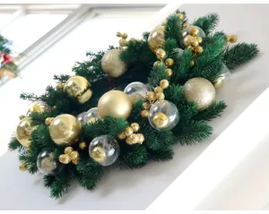 Macro view of a festive green pine wreath decorated with various gold and clear baubles.