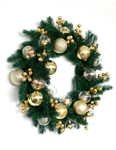 Close-up of lush green Christmas wreath with sparkling gold ornaments and berries.