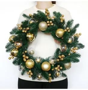 Luxurious Christmas wreath featuring gold ornaments and pine needles held by a model