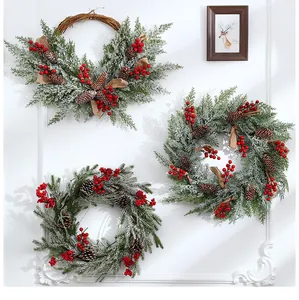Detailed view of three assorted snowy Christmas wreaths with red berries and pinecones