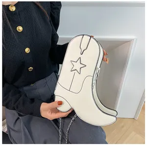 Détail d'un sac bandoulière blanc en forme de botte de cowboy avec étoile et chaîne argentée