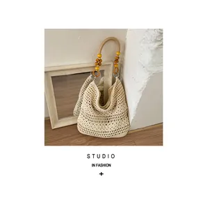 Detailed close-up of handmade crochet beach bag with decorative wooden bead handle