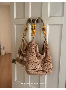 Side view of two hand-crocheted hobo bags with wooden bead handles hanging on a door