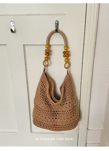 Large capacity hand-crocheted hobo beach bag with decorative beaded handle hanging on a door