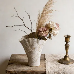 Detalle de jarrón de cerámica de arte francés con borde ondulado en mesa de madera