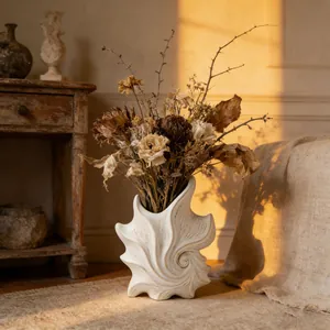 Artistic white ceramic spiral vase with dried flowers in warm sunset light