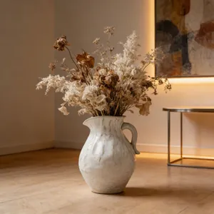 Detail of a white textured ceramic pitcher vase with dried flower arrangement