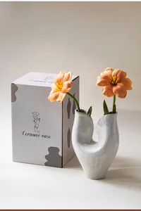 Modern white ceramic vase with abstract U-shape design next to its retail box
