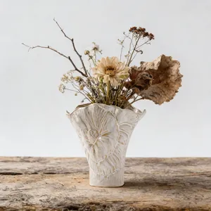 Jarrón de cerámica vintage con relieve floral y flores secas decorativas.