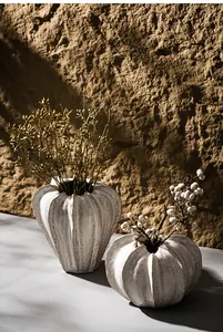 Detail of rustic white fluted ceramic vases with dried floral decor in warm light