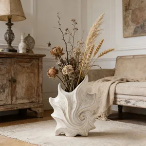 Artistic seashell-shaped ceramic vase with dried flowers in a vintage French interior.