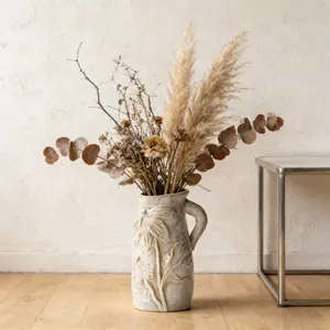 Dettaglio di una brocca di fiori in ceramica vintage bianco sporco con motivi a foglie in rilievo