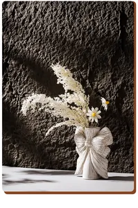 Detailed view of white ceramic vase with artistic bow design and dried flowers