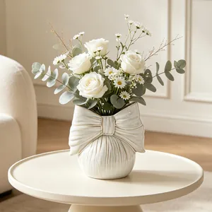 Detailed view of cream ceramic vase with elegant bow design and fresh white flowers