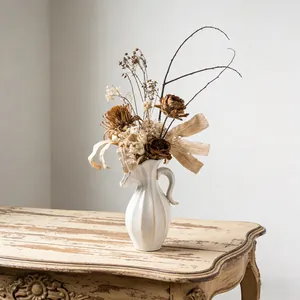 Elegante Noordse crèmewitte keramische vaas met droogbloemen op een houten tafel