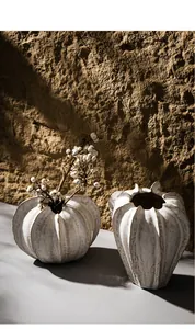 Close-up of white textured ceramic vases with minimalist organic shapes and dried berries.