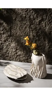 Detailed view of white wabi-sabi ceramic vases with organic textures and dried flowers.