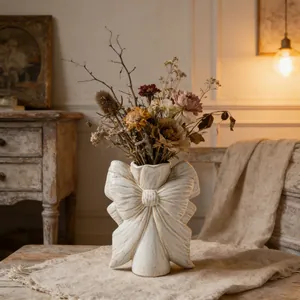 Vase vintage en céramique blanche avec nœud papillon et fleurs séchées sur table rustique