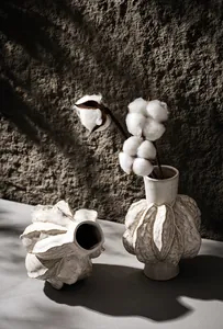 Artistic detail of textured white ceramic vases decorated with dried cotton branches
