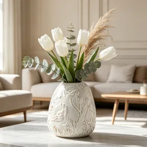 Detail of a cream ceramic vase with embossed floral patterns and white tulips.