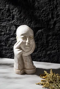 Close-up of an artistic white ceramic vase featuring a unique contemplative human face design