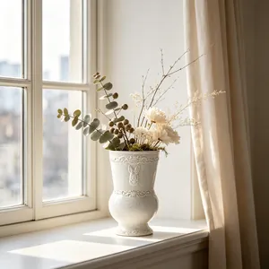 Detailed view of white ceramic vase with French vintage relief pattern on a sunlit windowsill