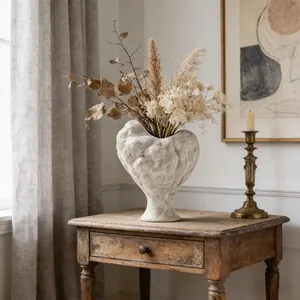 Detailed view of the irregular heart-shaped white ceramic vase on rustic table.