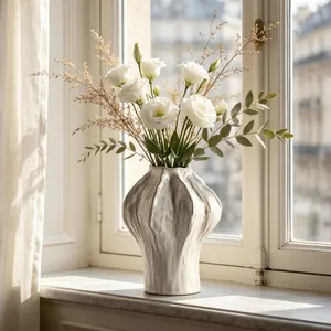 Detail of a white ceramic vase with organic wavy texture on a sunlit windowsill.