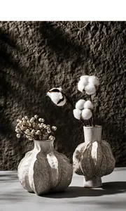 Detailed macro shot of irregular pleated textures on off-white ceramic flower vases