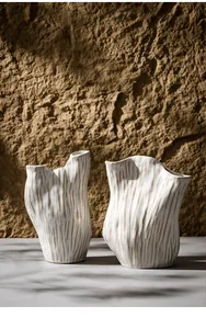 Detailansicht von Wabi-Sabi-Keramikvasen mit organischer Rippenstruktur vor Steinwand.