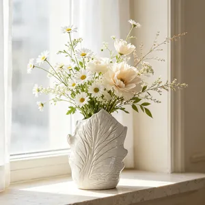 Close-up view of a white ceramic vase with leaf-vein texture and spring flowers