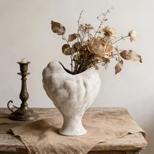 Artistic textured white ceramic heart-shaped vase with dried flowers for home decor